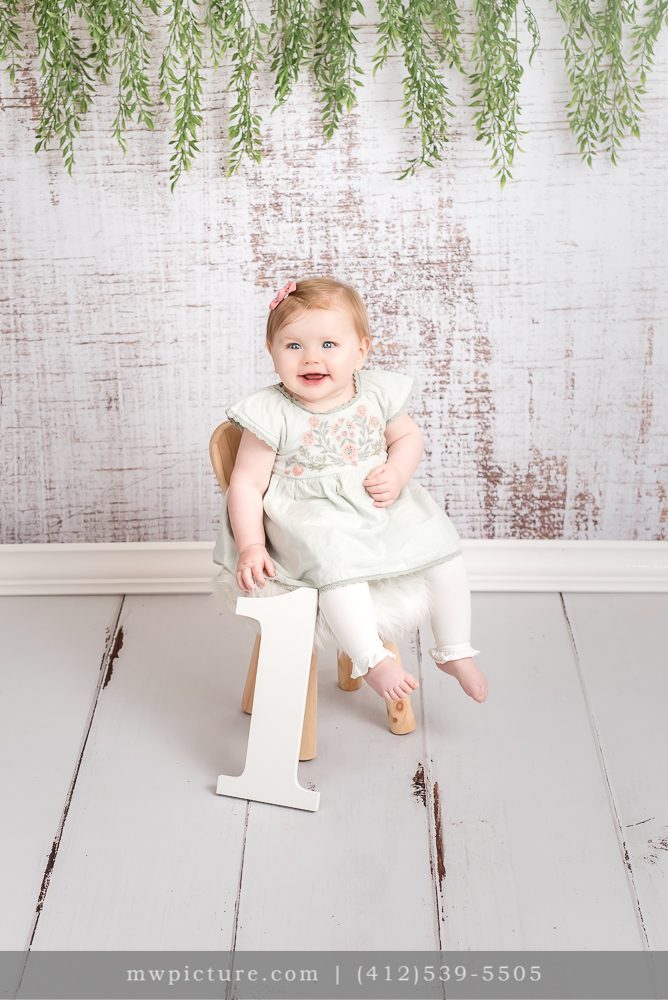 A One Year Old Child Sitting on Chair and Decorated Wall