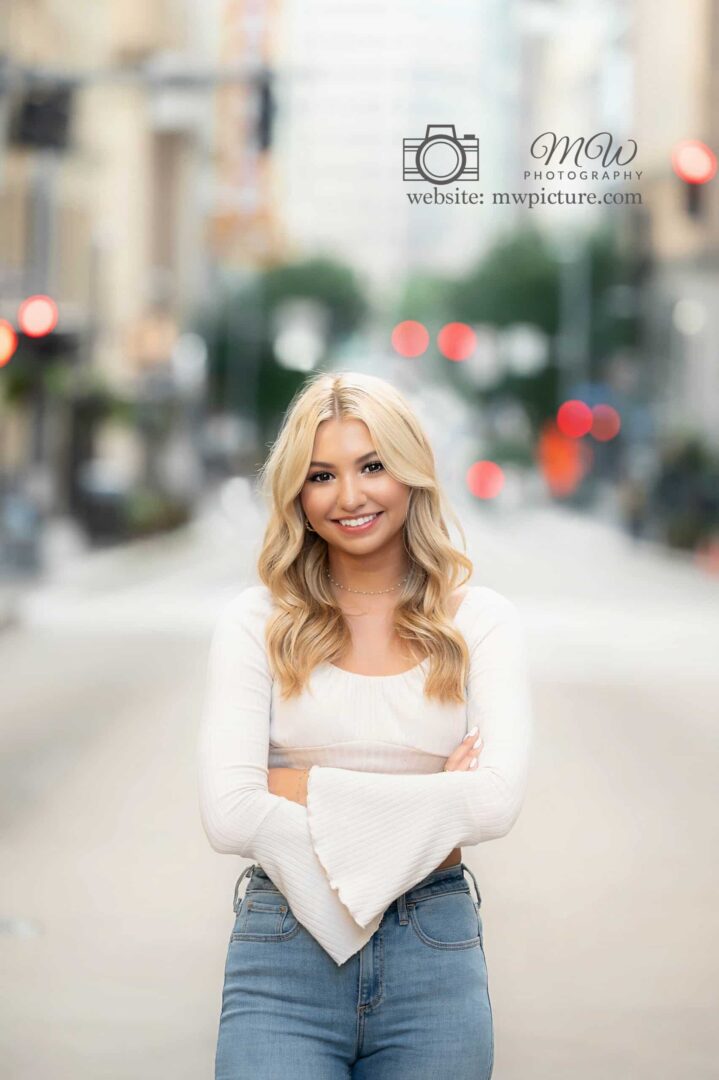 A beautiful blonde woman standing on the side of a road.