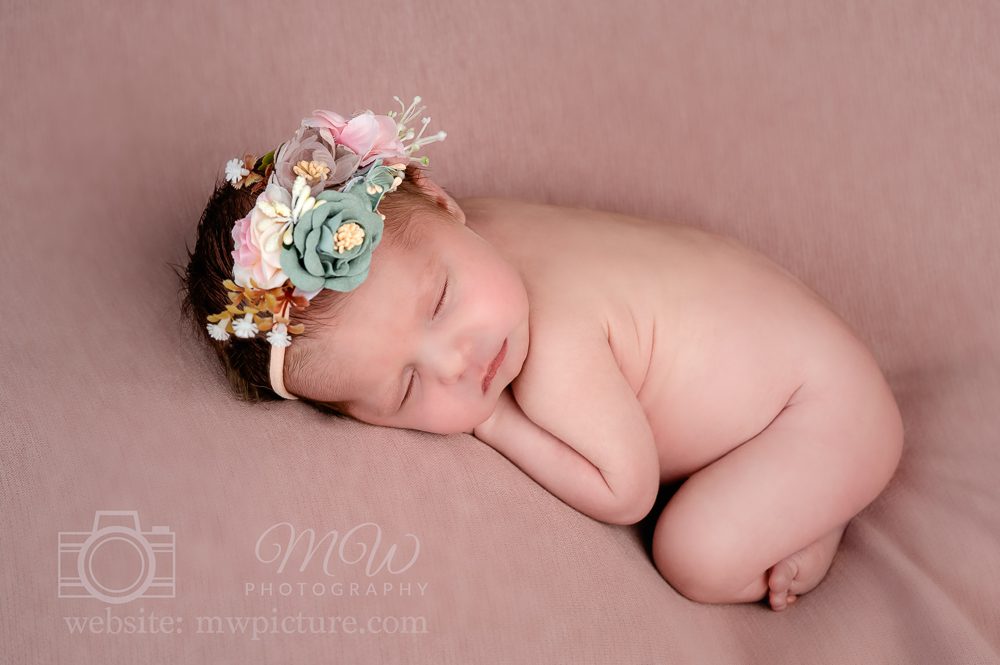 A baby girl wearing a flower crown is sleeping.