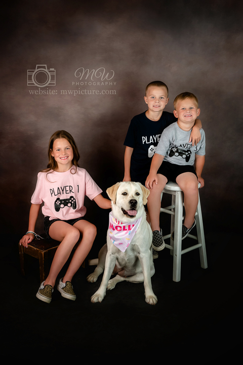 A group of kids and their dog pose for the camera.