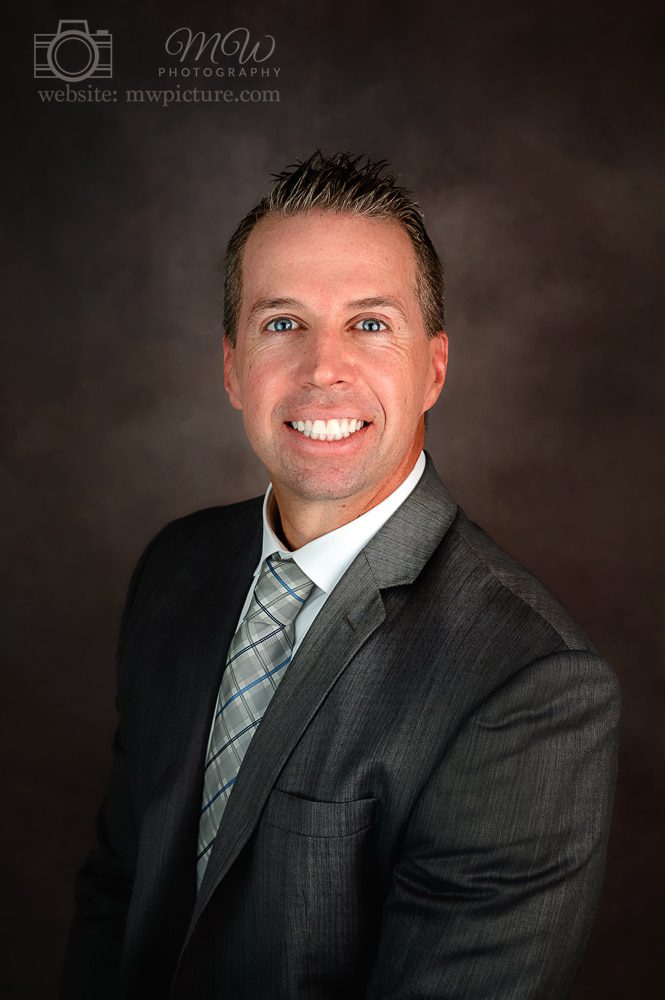 A man in a suit and tie smiling for the camera.