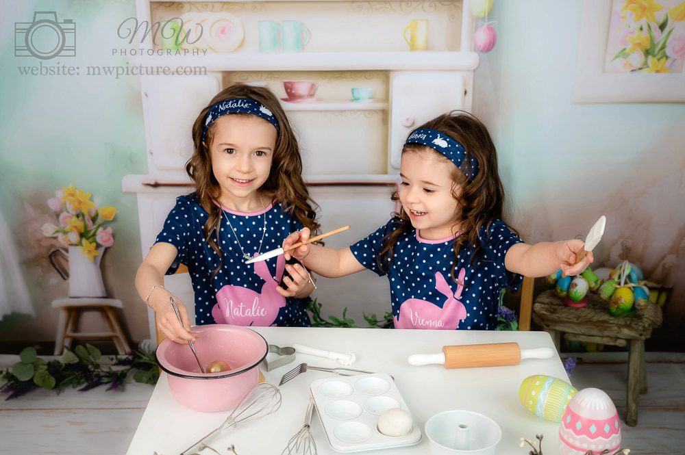 Two little girls are playing with a cake.