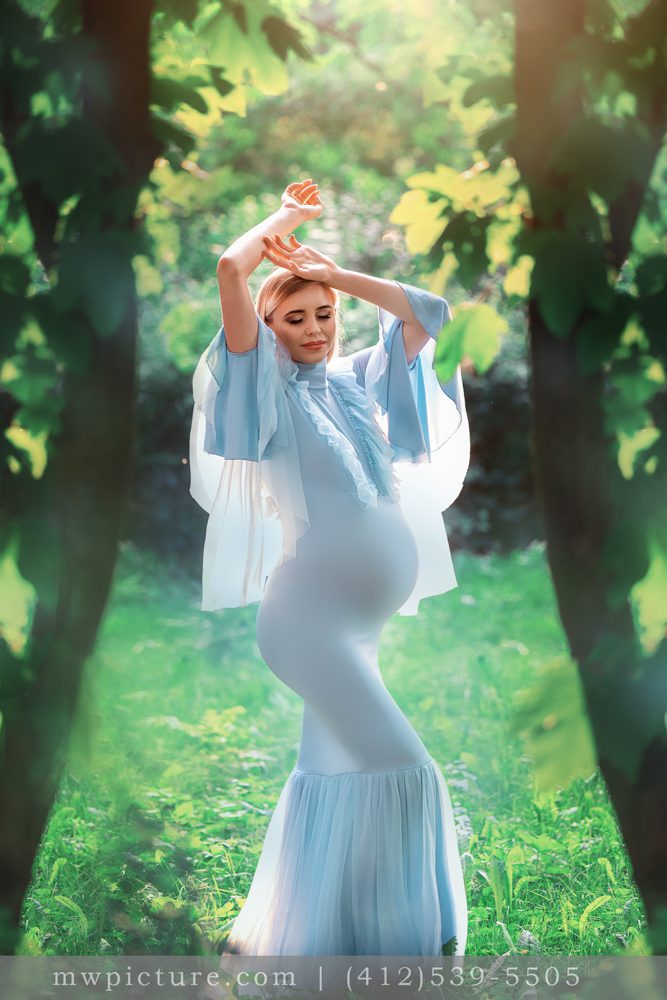 A woman in blue dress holding onto a tree