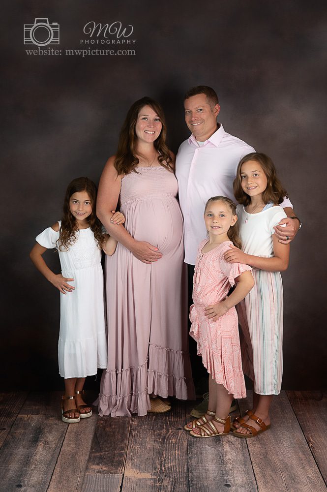 A family posing for a picture in front of a black wall.