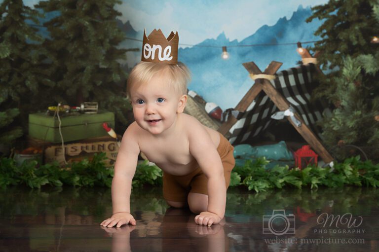 A baby boy wearing a paper crown and diaper.