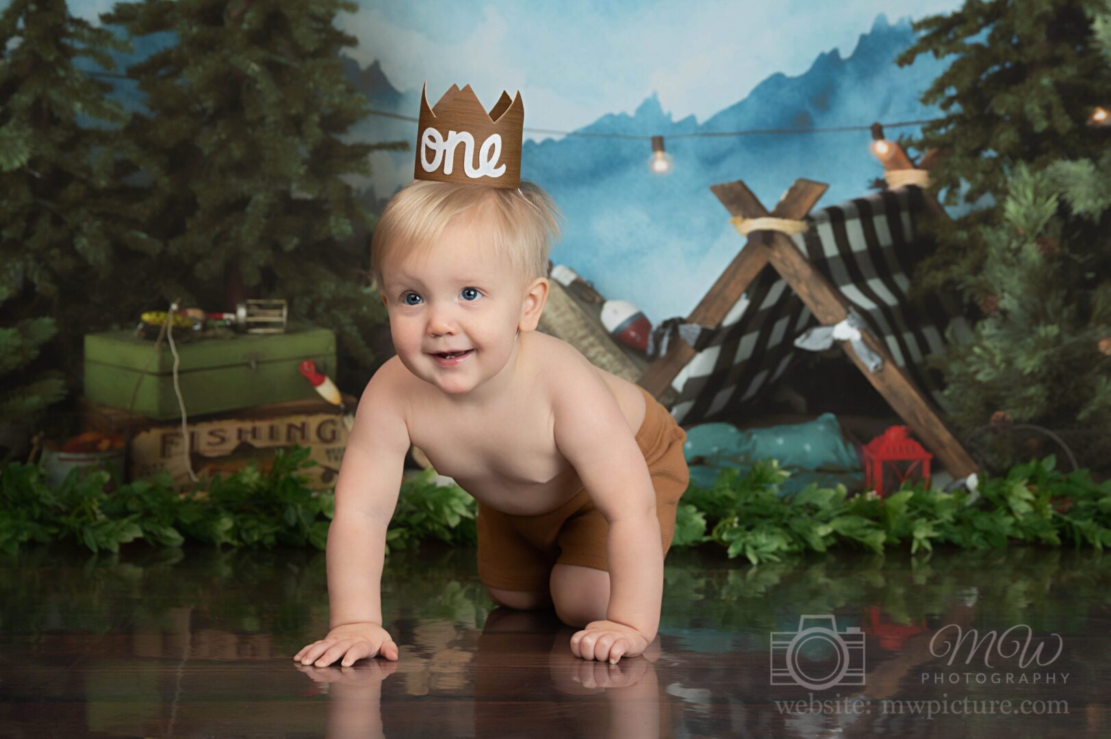 A baby boy wearing a paper crown and diaper.