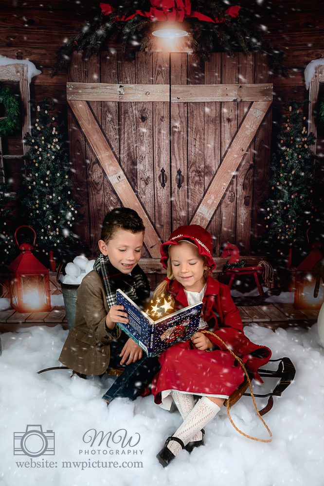 Two children sitting in front of a christmas tree.
