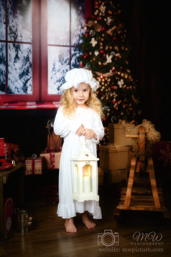 A little girl in white dress holding a lantern.