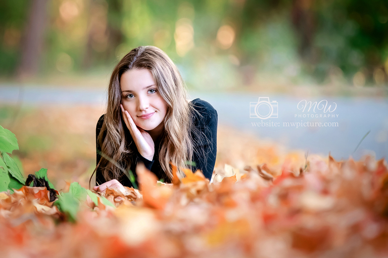 A woman laying on the ground in leaves.