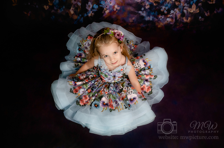 A little girl in a dress sitting on the floor