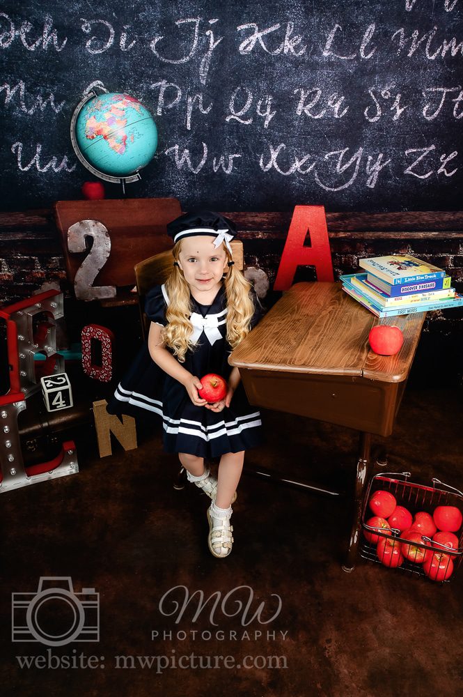 A little girl in sailor suit sitting at her desk.
